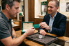Seller handing a warranty card to a new owner beside a Rolex Datejust and its presentation box.