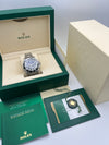Rolex watch in an open green and beige box with accessories on a light gray background